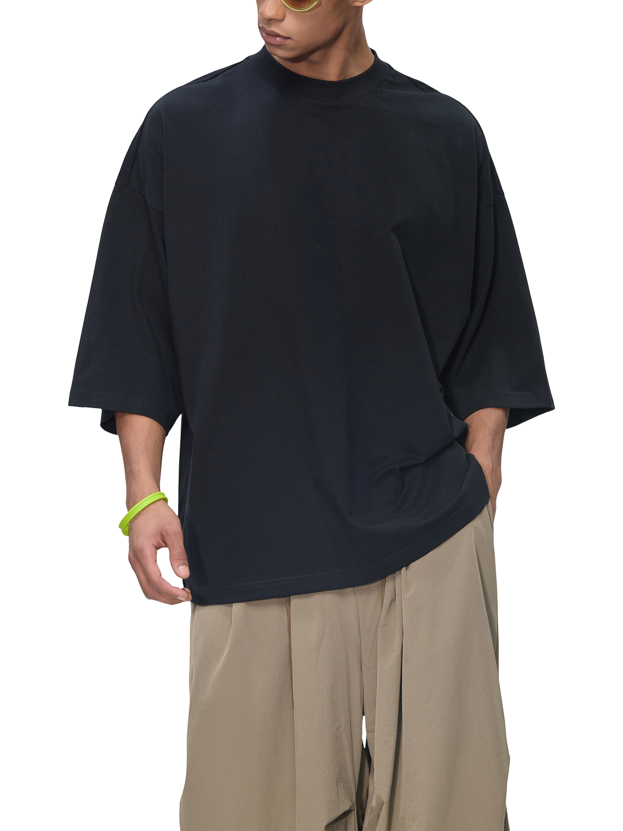 Person wearing a black oversized t-shirt and beige pants on a transparent background