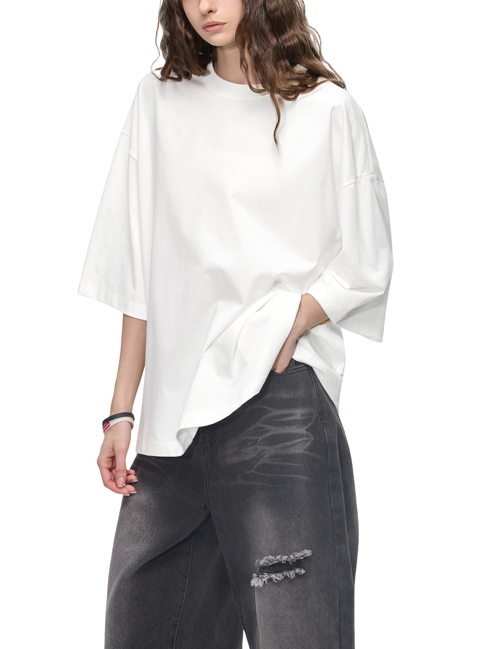 Person wearing a white oversized shirt and dark pants on a white background